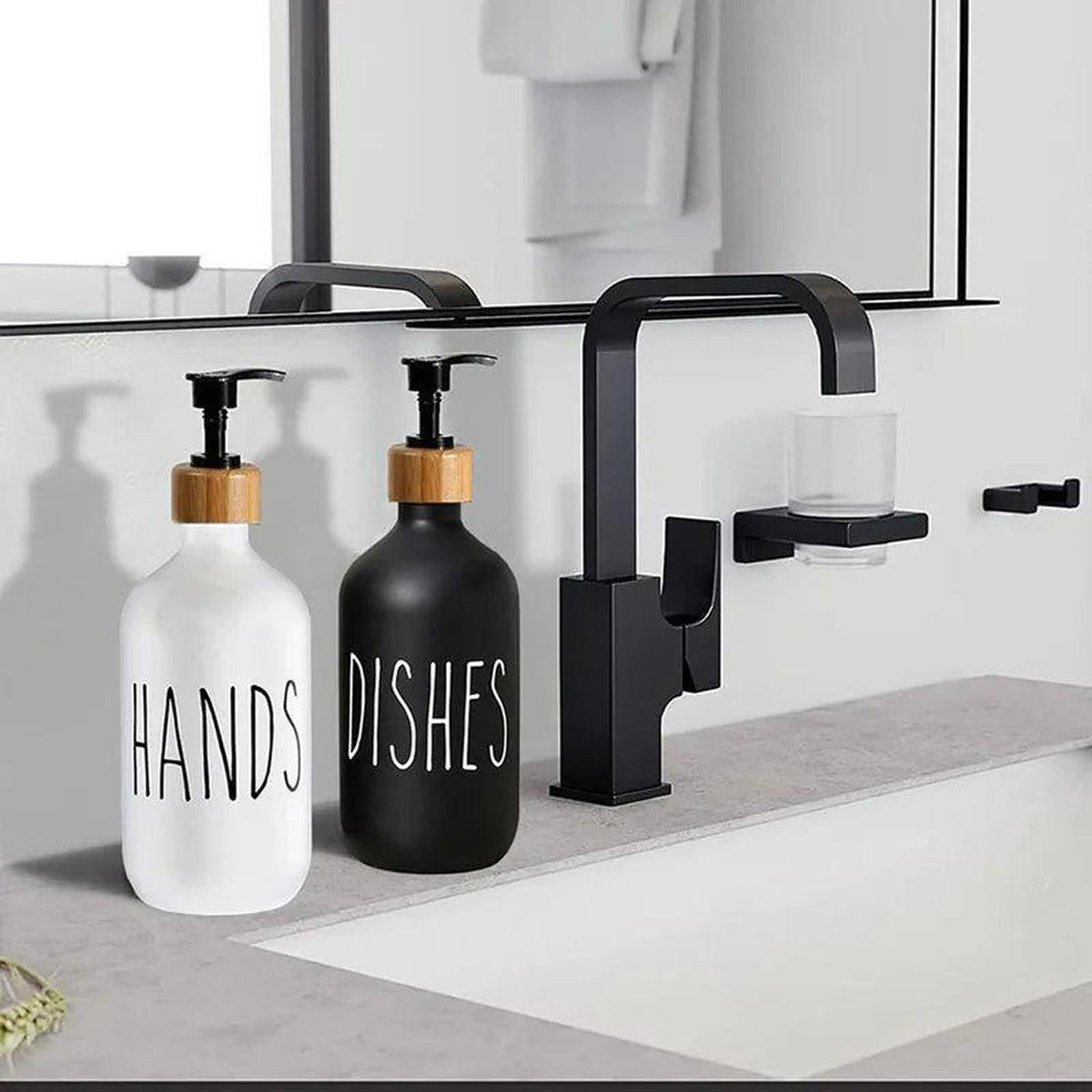 Refillable 500ml white and black soap dispensers with bamboo pumps on a modern bathroom vanity sink.