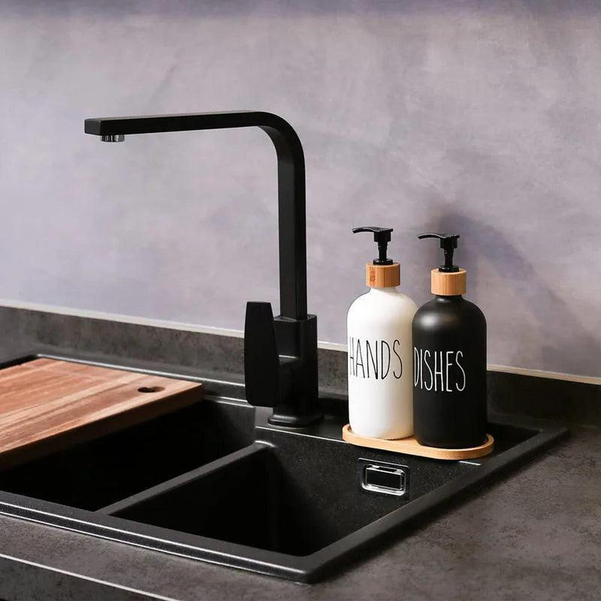 Black and white 500ml soap dispensers with bamboo pumps and tray on a modern kitchen sink.