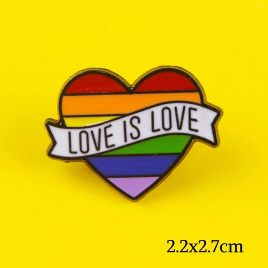 Heart-shaped rainbow enamel pin with a white banner reading Love is Love on a yellow background.