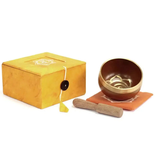 Sacral Chakra brass singing bowl with wooden mallet, orange cushion, and matching gift box on a white background.
