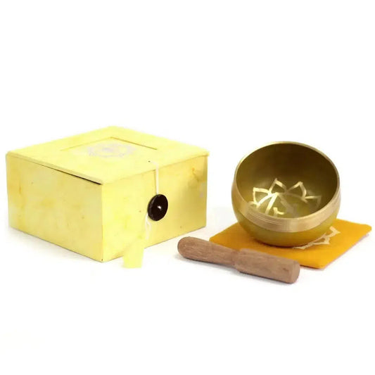 Golden brass singing bowl with lotus engraving, wooden striker, yellow cushion, and matching storage box.